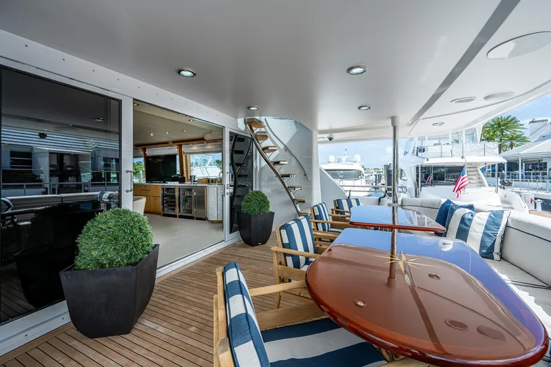 Wire We Here Yacht Photos Pics Luxury yacht Crescent Westport Pilothouse 1995, outdoor dining area with striped cushions and wooden table.