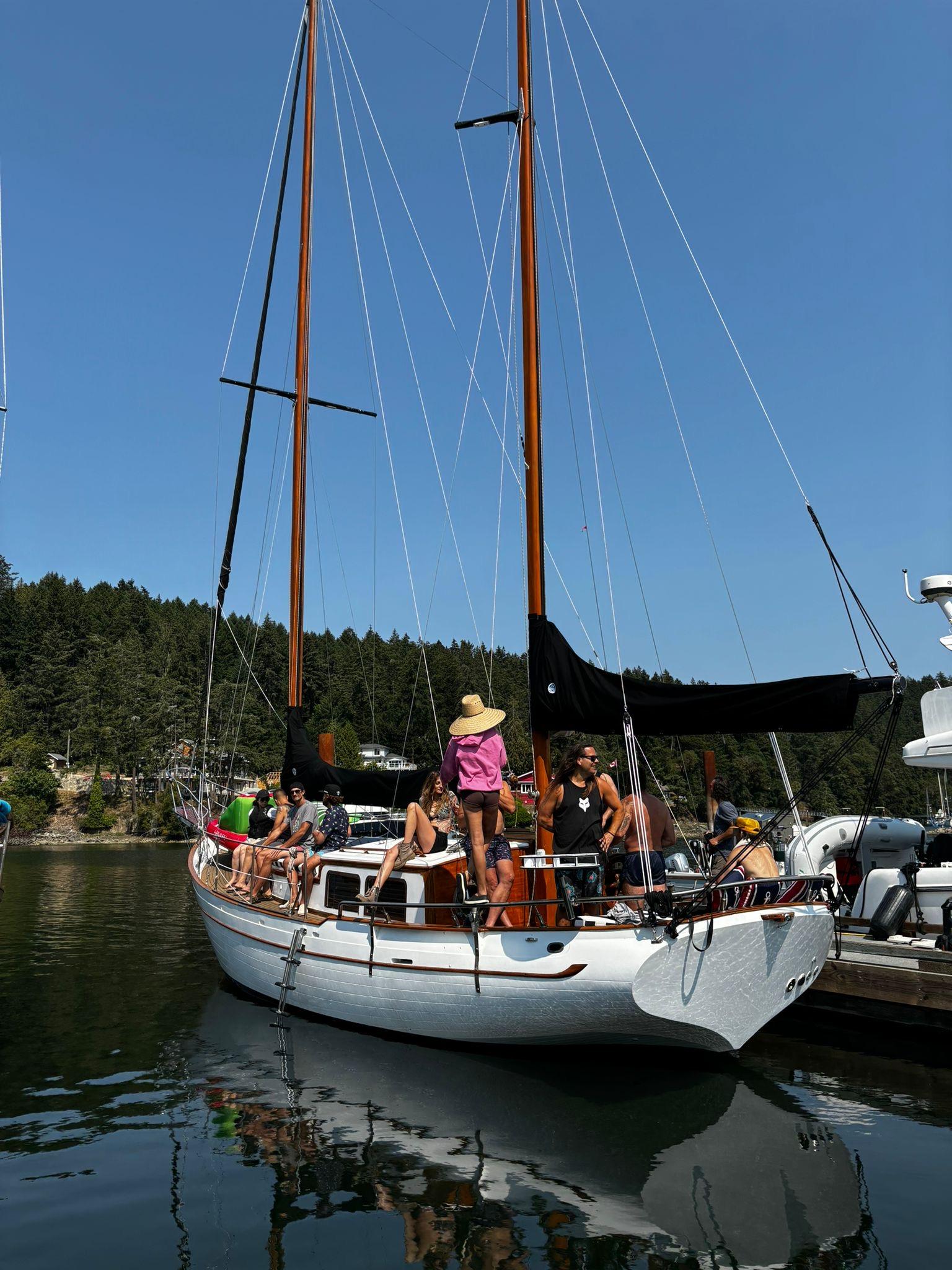 1976 CT 41 sailboat docked with people on board, clear sky, forested background.