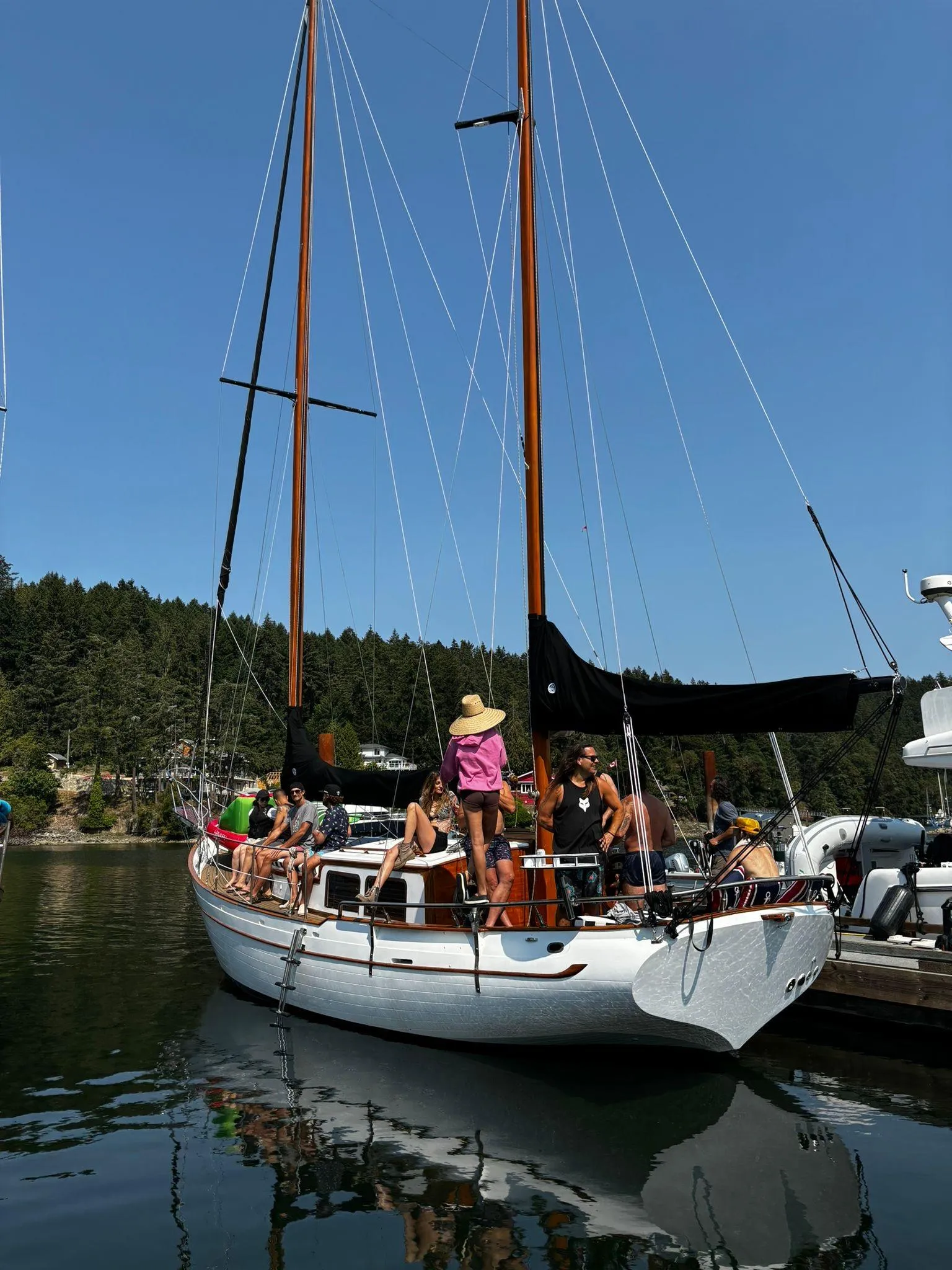 1976 CT 41 sailboat docked with people on board, clear sky, forested background.