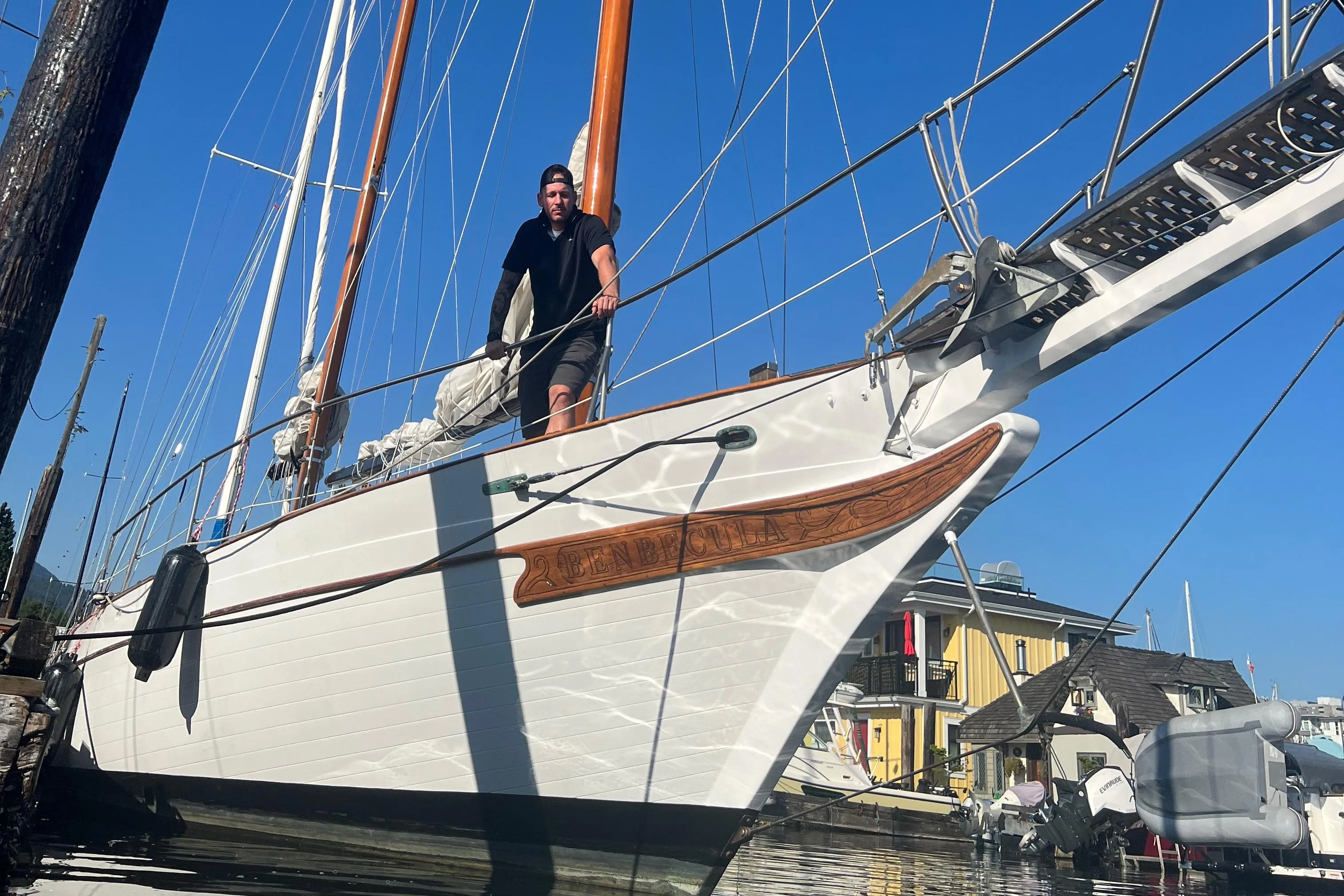 Man on 1976 CT 41 sailboat docked at marina, clear blue sky background.