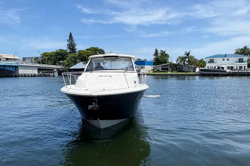 Lieuanna Yacht Photos Pics 2024 Pursuit OS 355 Offshore boat cruising on a calm waterway, surrounded by houses.