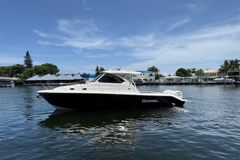 Lieuanna Yacht Photos Pics 2024 Pursuit OS 355 Offshore boat on calm water, with a scenic waterfront backdrop.