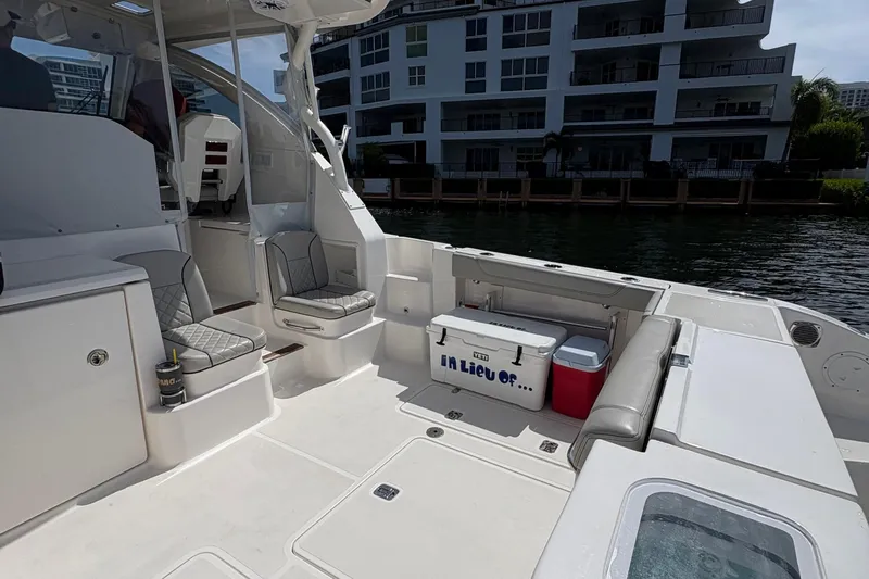 Lieuanna Yacht Photos Pics 2024 Pursuit OS 355 Offshore boat interior with seating and coolers, docked near waterfront buildings.