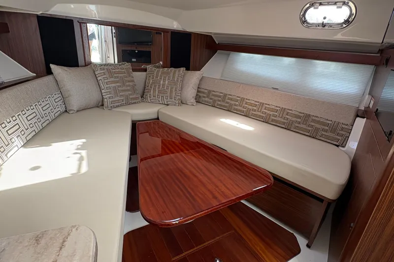 Lieuanna Yacht Photos Pics 2024 Pursuit OS 355 Offshore cabin interior with plush seating and wooden table.