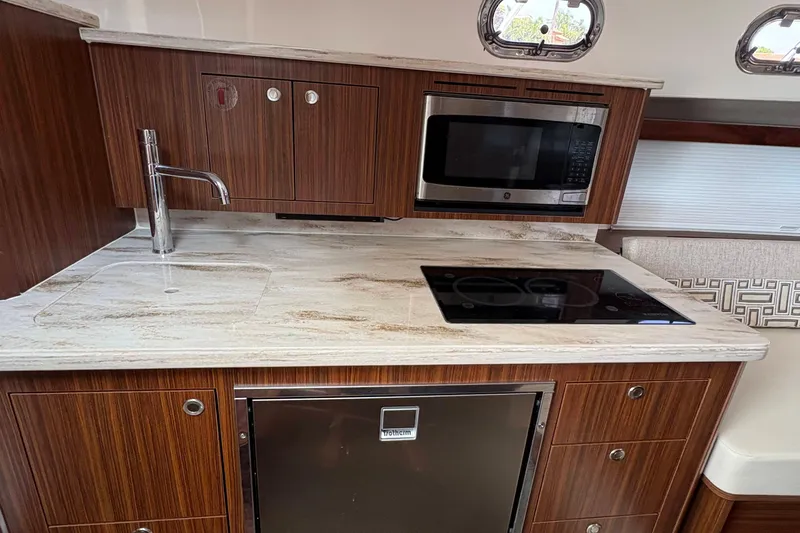 Lieuanna Yacht Photos Pics 2024 Pursuit OS 355 Offshore yacht kitchen with wood cabinetry, microwave, and stovetop.