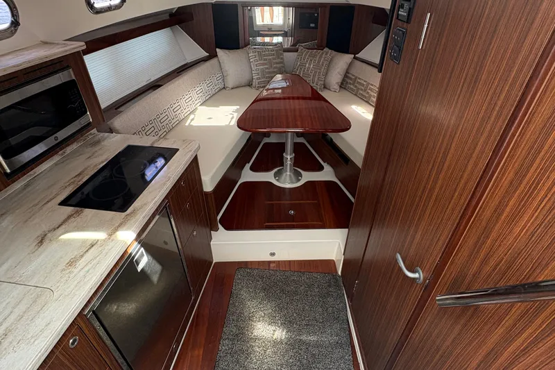 Lieuanna Yacht Photos Pics 2024 Pursuit OS 355 Offshore cabin interior with wood finish, kitchenette, and seating area.