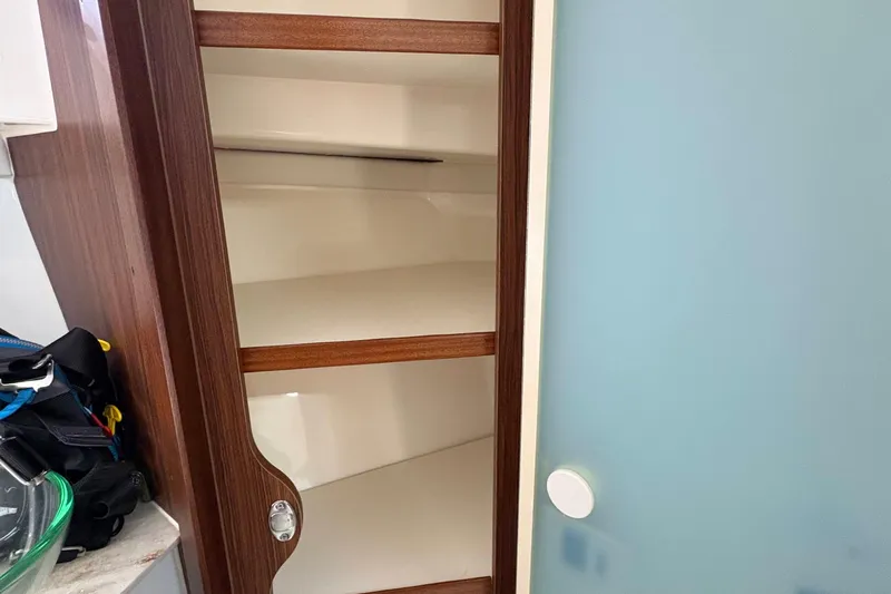 Lieuanna Yacht Photos Pics 2024 Pursuit OS 355 Offshore interior cabinet with wooden shelves and frosted glass door.