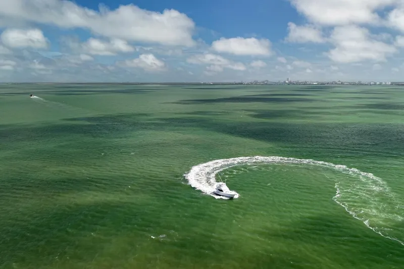 Loca Louise Yacht Photos Pics Aerial view of 2002 Hatteras 50 Convertible yacht making a circular wake in green ocean.
