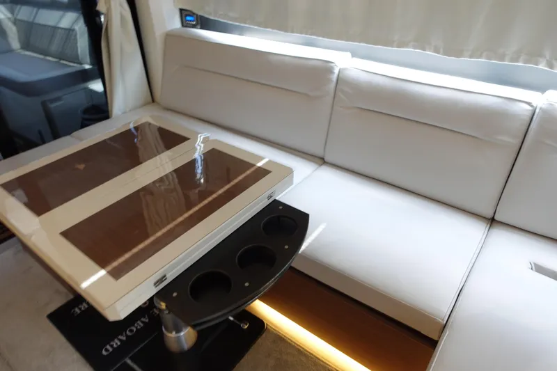 Somedays Here Yacht Photos Pics Interior of 2021 Jeanneau NC 37 yacht with white seating and a wooden table.