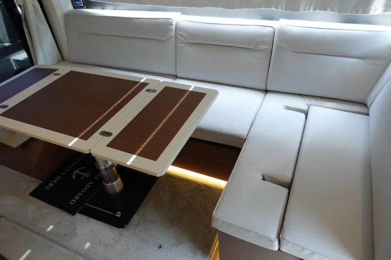 Somedays Here Yacht Photos Pics Interior of 2021 Jeanneau NC 37 yacht with white seating and wooden table.