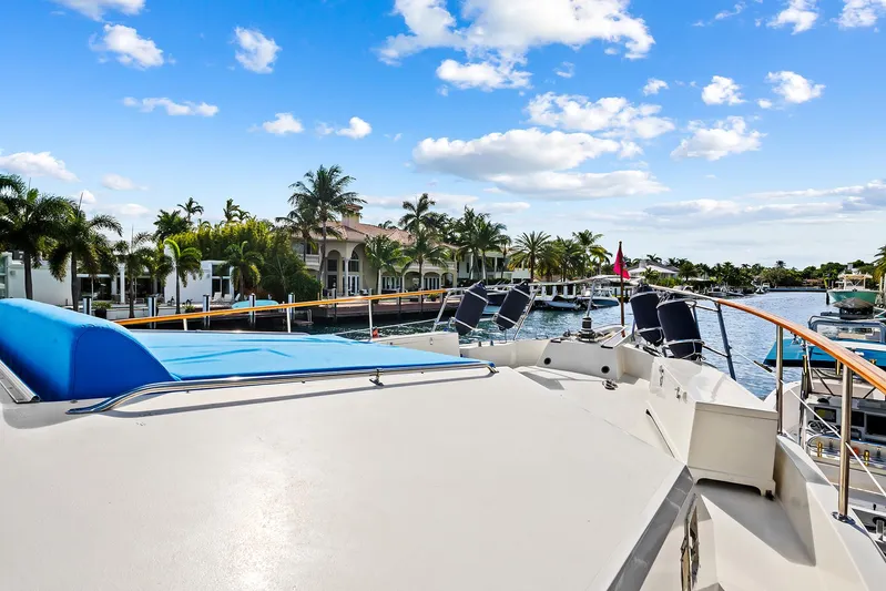  Yacht Photos Pics 1989 Hatteras 70 Motor Yacht docked near waterfront homes under a blue sky.