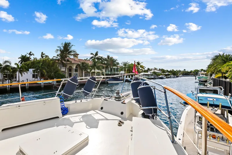  Yacht Photos Pics 1989 Hatteras 70 Motor Yacht on a sunny waterfront with palm trees.