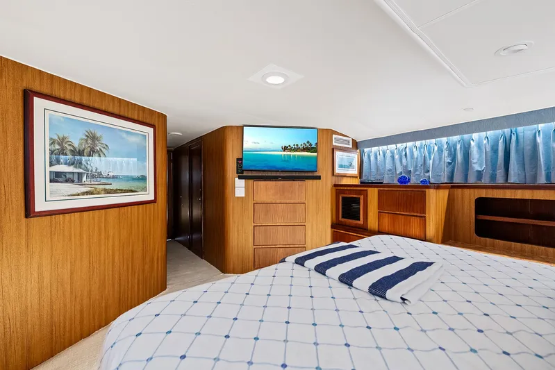  Yacht Photos Pics 1989 Hatteras 70 Motor Yacht bedroom with wood paneling, TV, and nautical decor.