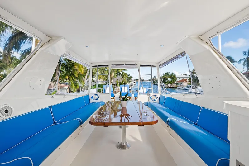  Yacht Photos Pics Interior of 1989 Hatteras 70 Motor Yacht with blue seating and wooden table.