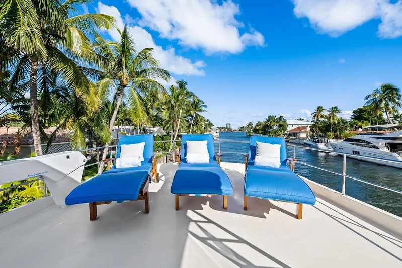  Yacht Photos Pics Deck of 1989 Hatteras 70 Motor Yacht with blue lounge chairs, palm trees, and waterfront view.