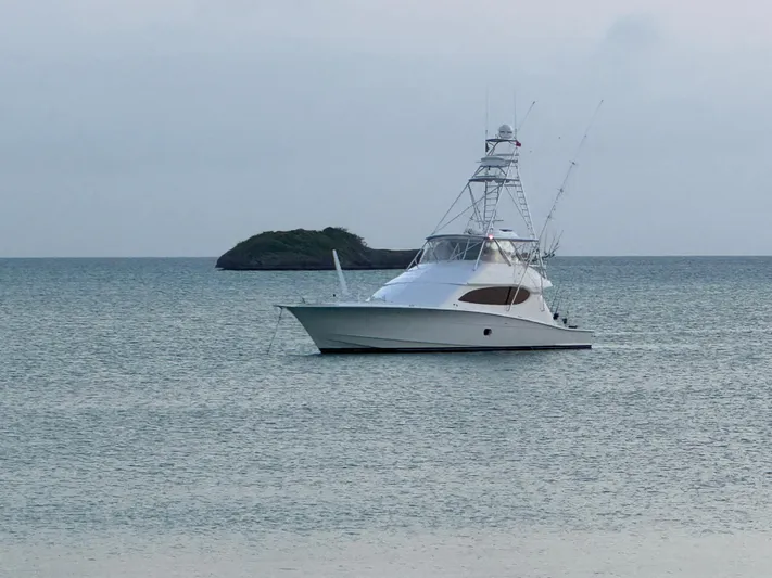 Cast Away Yacht Photos Pics 2008 Hatteras 68 Convertible yacht anchored in calm waters near a small island.