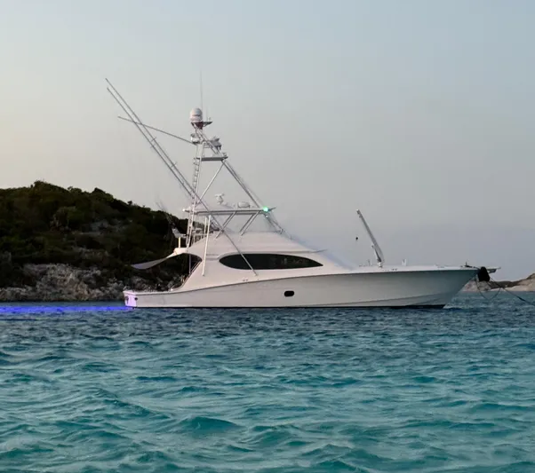 Cast Away Yacht Photos Pics 2008 Hatteras 68 Convertible yacht anchored in clear blue waters near a rocky shoreline.