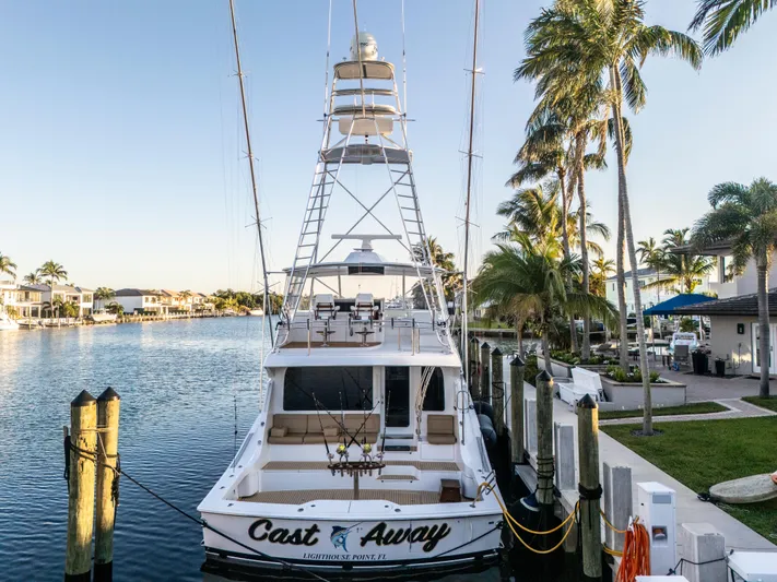 Cast Away Yacht Photos Pics 2008 Hatteras 68 Convertible yacht docked by palm trees, rear view.