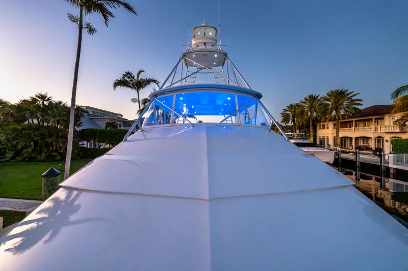 Cast Away Yacht Photos Pics 2008 Hatteras 68 Convertible yacht with blue lighting, docked near palm trees at sunset.
