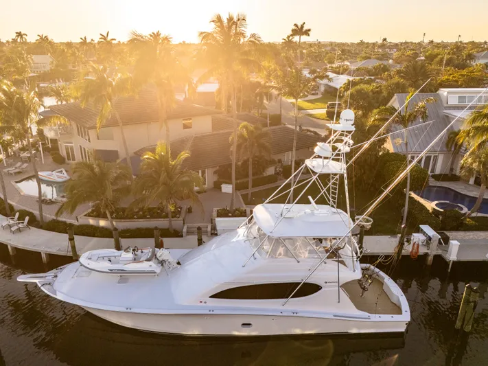 Cast Away Yacht Photos Pics 2008 Hatteras 68 Convertible yacht docked at sunset, surrounded by palm trees and waterfront homes.