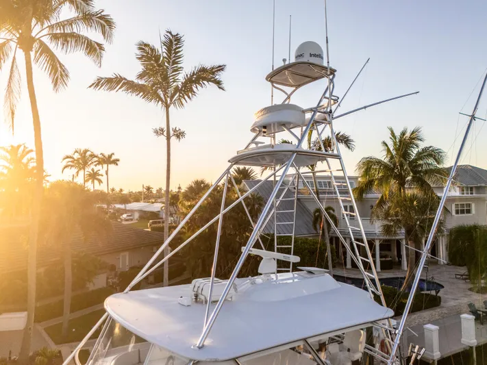 Cast Away Yacht Photos Pics 2008 Hatteras 68 Convertible yacht with tower, surrounded by palm trees at sunset.