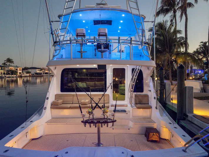 Cast Away Yacht Photos Pics 2008 Hatteras 68 Convertible yacht with illuminated deck at sunset, docked near palm trees.