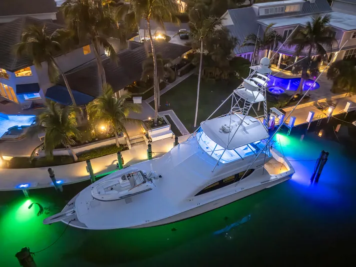 Cast Away Yacht Photos Pics 2008 Hatteras 68 Convertible yacht docked, illuminated by vibrant underwater lights.