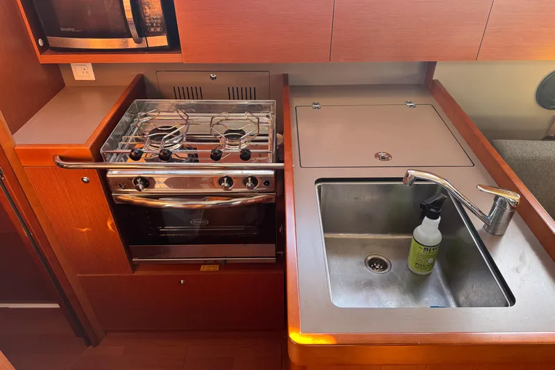 Viento Yacht Photos Pics Compact kitchen in 2018 Beneteau Oceanis 35.1 yacht with stove, sink, and microwave.
