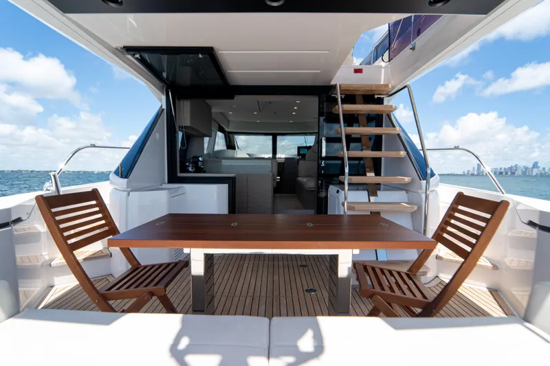 Avanti Yacht Photos Pics Luxurious 2022 Ferretti Yachts 500 deck with wooden table and chairs, ocean view.