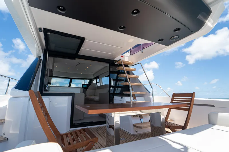 Avanti Yacht Photos Pics Luxurious 2022 Ferretti Yachts 500 deck with wooden chairs and table under blue sky.