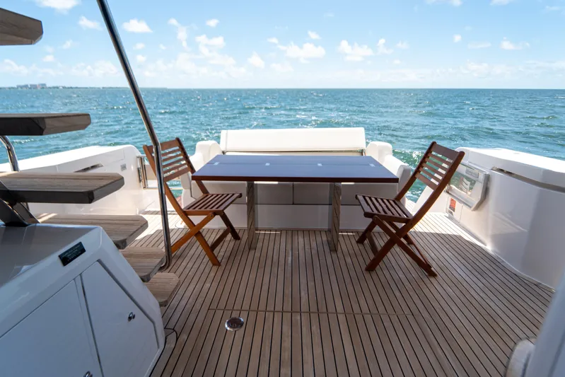Avanti Yacht Photos Pics 2022 Ferretti Yachts 500 deck with wooden chairs and table, ocean view.