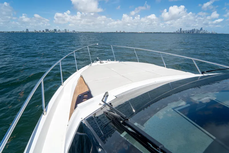 Avanti Yacht Photos Pics Ferretti Yachts 500 cruising on open water, city skyline in background, 2022 model.