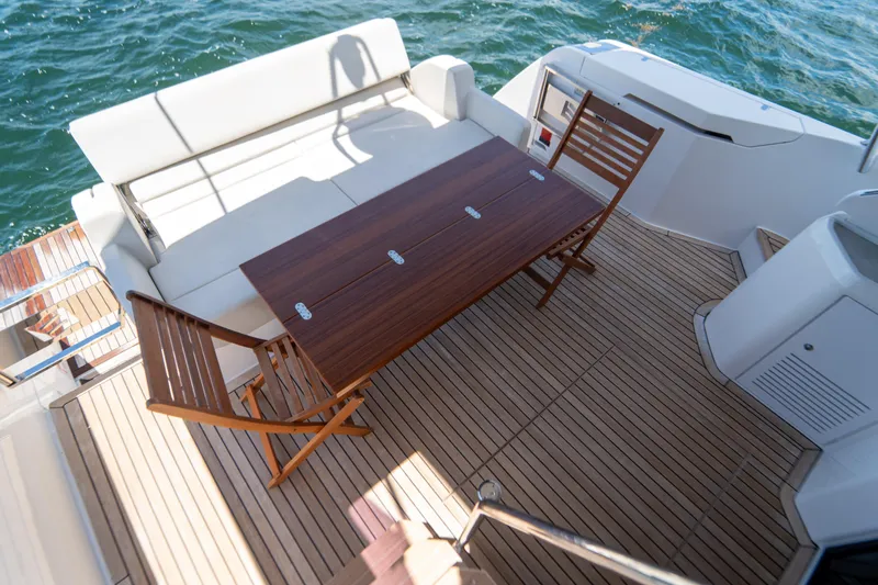 Avanti Yacht Photos Pics Deck of 2022 Ferretti Yachts 500 with wooden table and chairs, overlooking the sea.