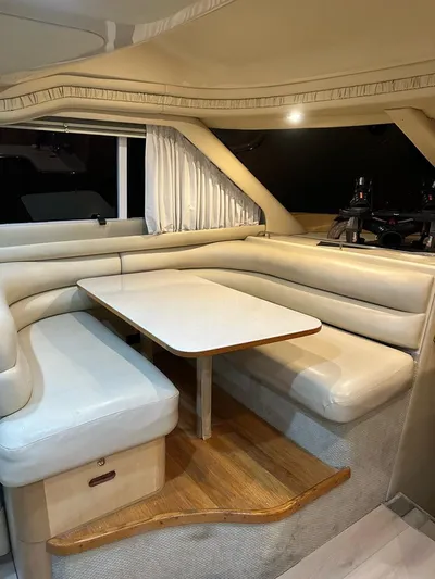 Chiquimu Yacht Photos Pics 2000 Sea Ray 480 Sedan Bridge interior with beige seating and wooden table.