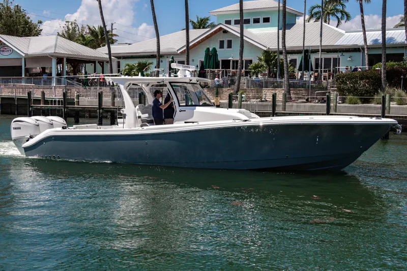  Yacht Photos Pics 2025 Edgewater 370CC boat cruising near waterfront buildings and palm trees.
