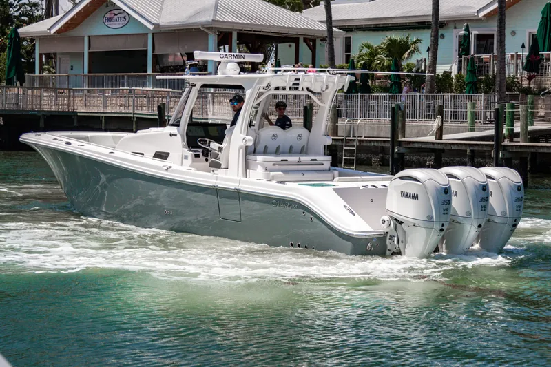  Yacht Photos Pics 2025 Edgewater 370CC boat with triple Yamaha engines cruising near a dock.