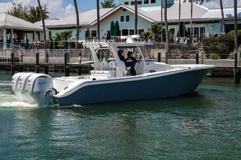  Yacht Photos Pics 2025 Edgewater 370CC boat cruising near a waterfront restaurant.