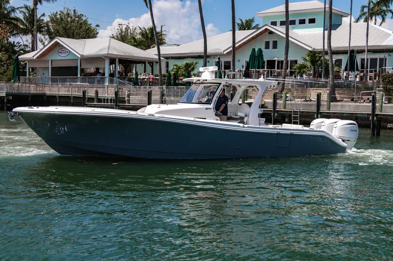  Yacht Photos Pics 2025 Edgewater 370CC boat cruising near a waterfront restaurant.