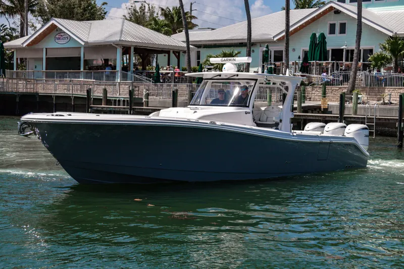  Yacht Photos Pics 2025 Edgewater 370CC boat cruising near a waterfront restaurant.