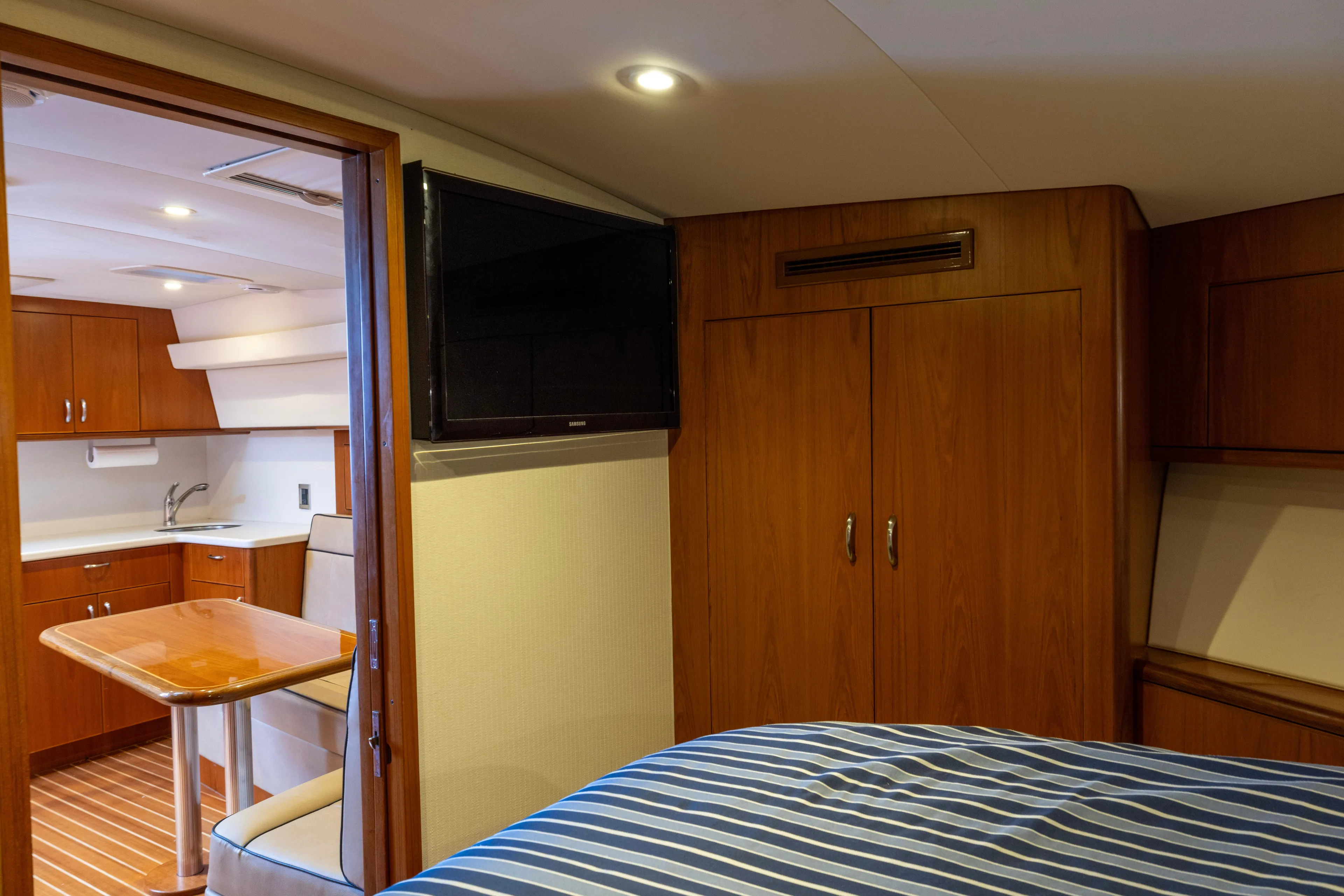  Yacht Photos Pics Interior of 2012 Cabo 44 Hardtop Express yacht with wood cabinetry and striped bedding.