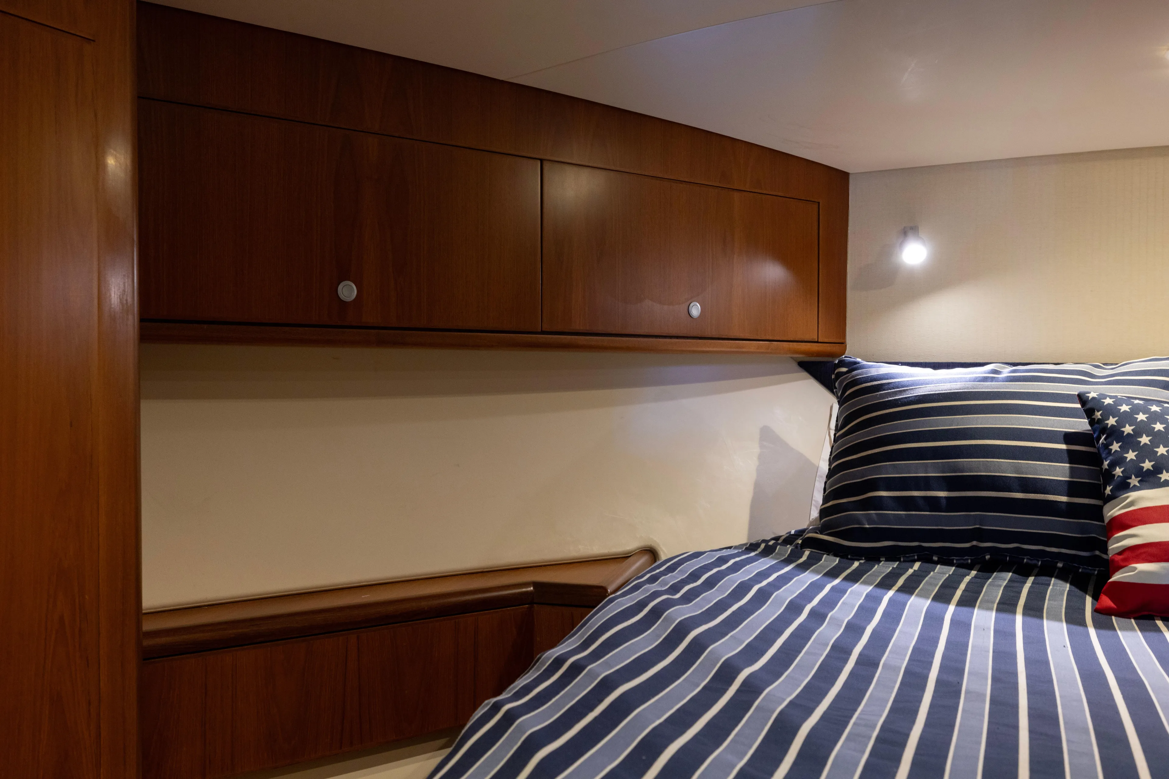  Yacht Photos Pics Cozy cabin interior of 2012 Cabo 44 Hardtop Express with striped bedding and wooden cabinets.