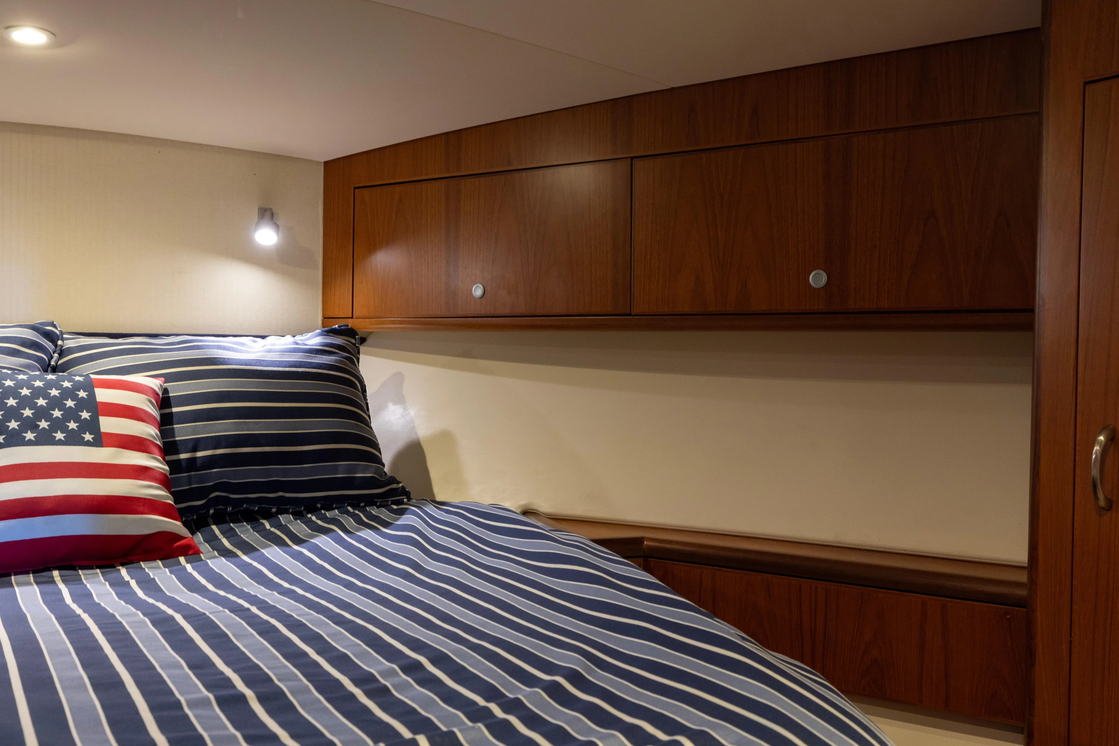  Yacht Photos Pics Cozy cabin interior of 2012 Cabo 44 Hardtop Express with striped bedding and wooden cabinets.