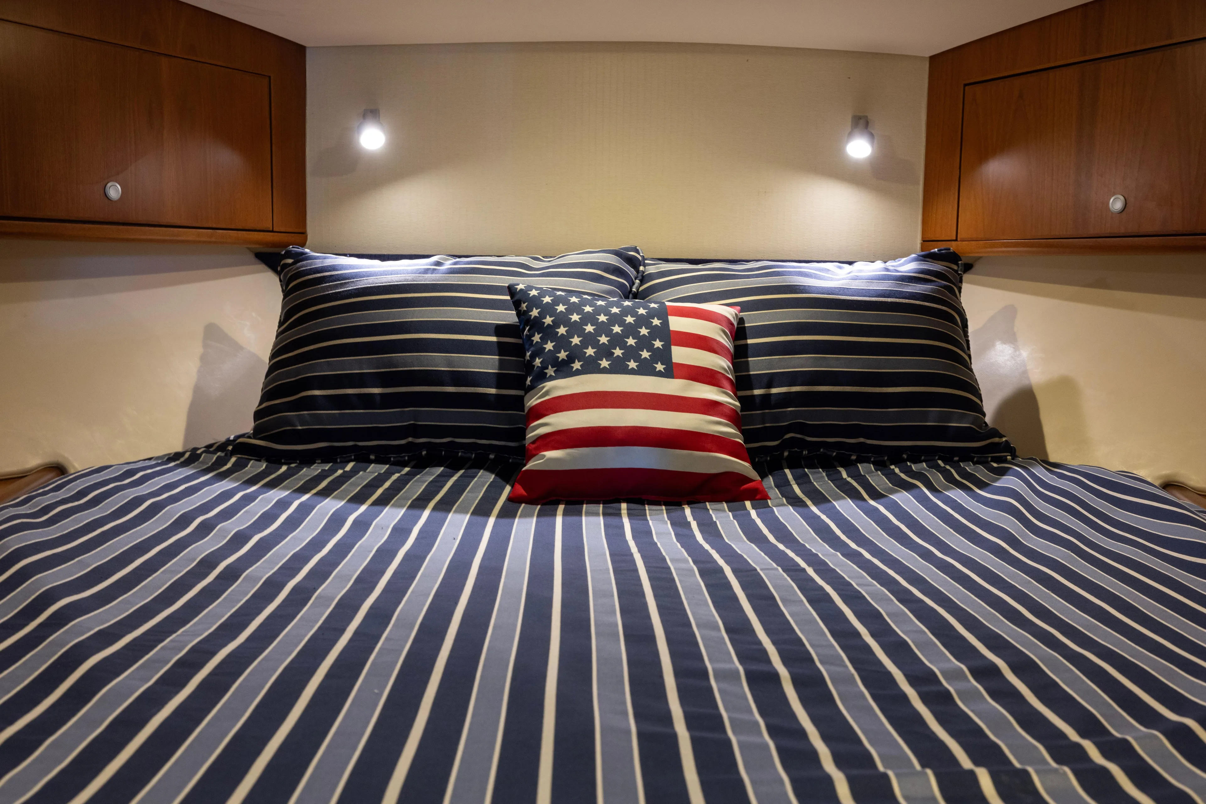  Yacht Photos Pics Cozy cabin bed in 2012 Cabo 44 Hardtop Express with striped bedding and American flag pillow.