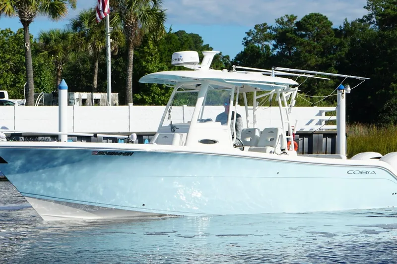  Yacht Photos Pics 2020 Cobia 301 Center Console boat on water, surrounded by trees and dock.