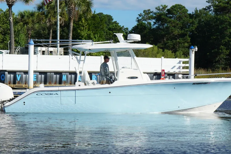  Yacht Photos Pics 2020 Cobia 301 Center Console boat docked near marina with lush greenery.
