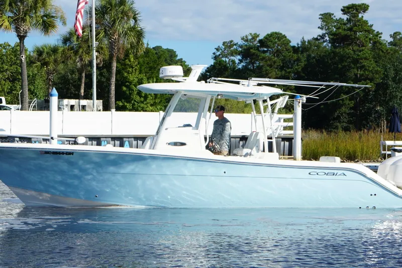  Yacht Photos Pics 2020 Cobia 301 Center Console boat on water, surrounded by trees and dock.