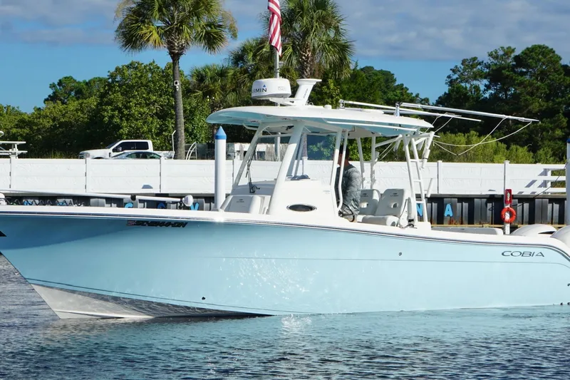  Yacht Photos Pics 2020 Cobia 301 Center Console boat on water, with palm trees and dock in background.