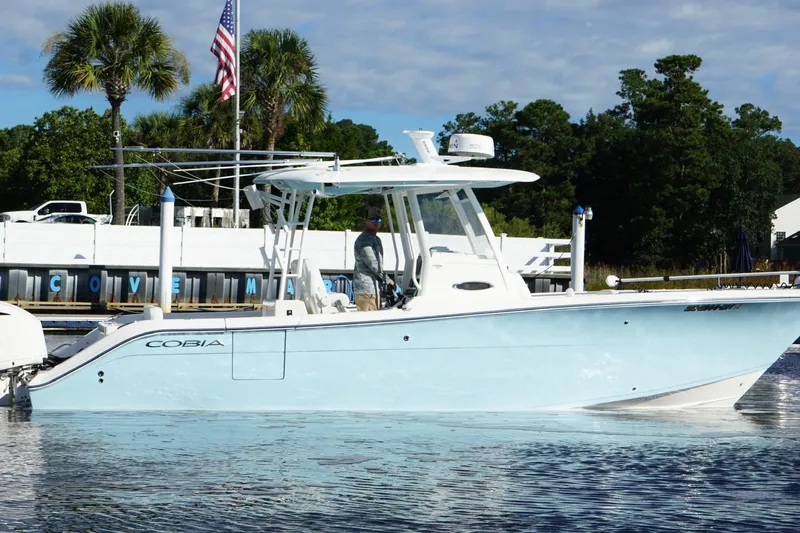  Yacht Photos Pics 2020 Cobia 301 Center Console boat docked, with American flag and palm trees in background.