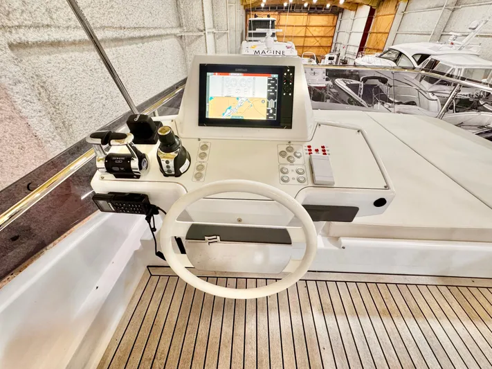 Time To Fly Yacht Photos Pics 2022 Ferretti Yachts 550 helm with navigation display and controls in a marina setting.