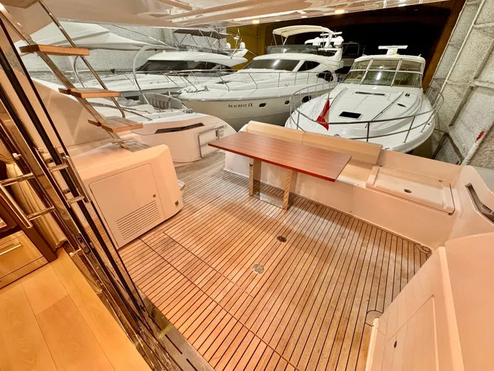 Time To Fly Yacht Photos Pics 2022 Ferretti Yachts 550 interior with wooden deck and seating area in a marina.